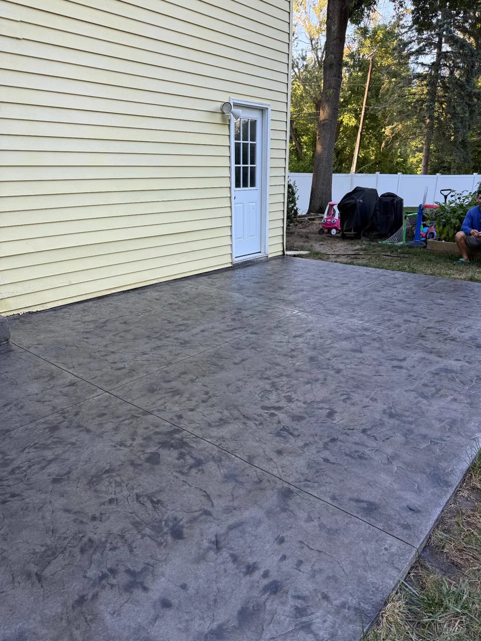 Wide view of a completed dark gray stamped concrete patio project