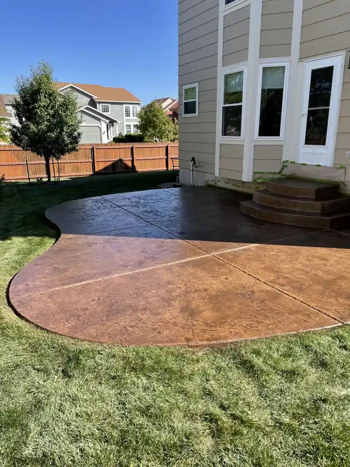 Stamped concrete patio mid-project showing faded concrete next to restored antiqued color
